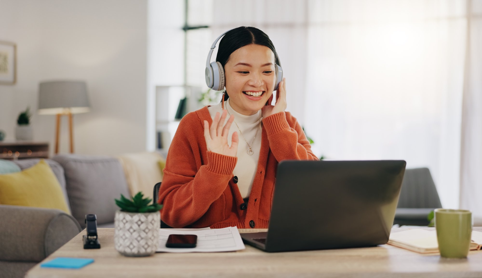 None-Stock-Woman on video call with work from home laptop, headphones and virtual international online meeting. Hello, wave and asian person in China in webinar for remote working or global updat